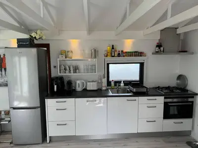 a kitchen with white cabinets and a stainless steel refrigerator at Holiday Home in Wervershoof mit Terrasse und Garten by Interhome in Wervershoof