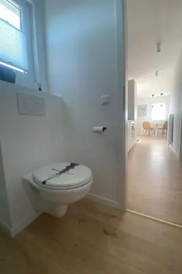 a white bathroom with a toilet with a black design on it at Holiday Home Sonnenschein by Interhome in Wervershoof