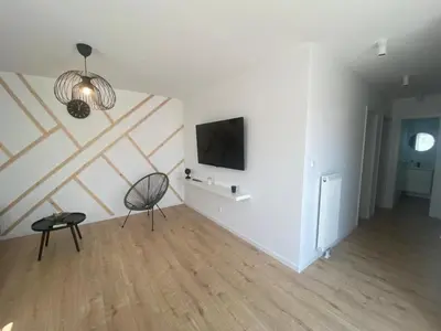 a living room with a chair and a television on a wall at Holiday Home Sonnenschein by Interhome in Wervershoof