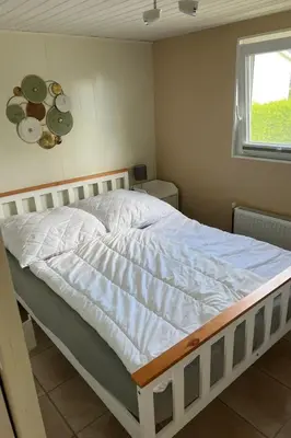 a white bed in a room with a window at Holiday Home Charmantes Ferienhaus Hilda mit Terrasse by Interhome in Wervershoof
