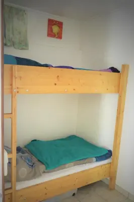 a wooden bunk bed with a green sheet on it at Holiday Home by Interhome in Wervershoof