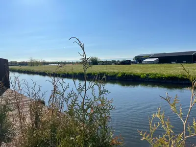 a river with a field and a building in the background at Holiday Home Haus Jeff by Interhome in Wervershoof