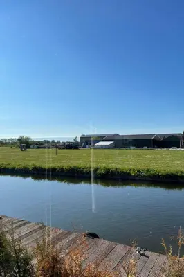 a pond in front of a field and a building at Holiday Home Haus Jeff by Interhome in Wervershoof