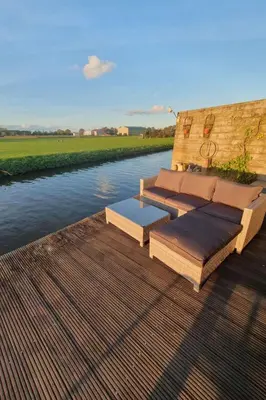 a bench sitting on a deck next to a river at Holiday Home Chalet op Zee by Interhome in Wervershoof