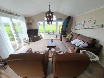 a living room with a couch and a table at Holiday Home Chalet op Zee by Interhome in Wervershoof