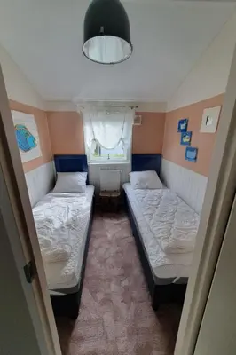 two beds in a small room with a window at Holiday Home Chalet op Zee by Interhome in Wervershoof