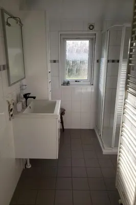 a white bathroom with a sink and a window at Holiday Home Chalet op Zee by Interhome in Wervershoof