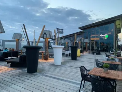 a wooden deck with tables and chairs and a building at Holiday Home in Dirkshorn by Interhome in Dirkshorn
