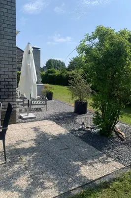 a patio with two benches and a white umbrella at Holiday Home in Dirkshorn by Interhome in Dirkshorn