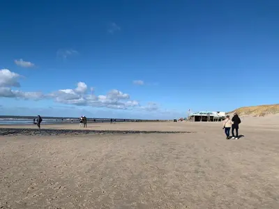 a group of people walking on the beach at Holiday Home in Dirkshorn by Interhome in Dirkshorn