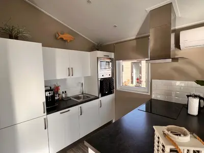 a small kitchen with white cabinets and a window at Holiday Home Exklusive Ferienhäuser Markermeer by Interhome in Bovenkarspel