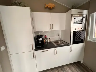 a small kitchen with white cabinets and a sink at Holiday Home Exklusive Ferienhäuser Markermeer by Interhome in Bovenkarspel