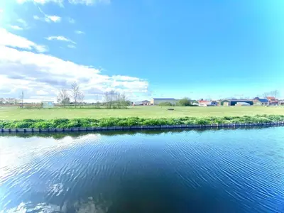 a body of water with a grassy field and sky at Holiday Home Isabella by Interhome in Wervershoof