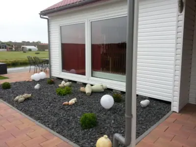 a garden with eggs on the ground next to a house at Holiday Home Auszeit direkt am Wasser by Interhome in Wervershoof