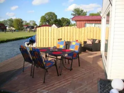 a patio with a table and chairs next to the water at Holiday Home Auszeit direkt am Wasser by Interhome in Wervershoof