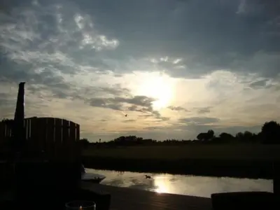 a sunset over a pond with the sun in the sky at Holiday Home Auszeit direkt am Wasser by Interhome in Wervershoof
