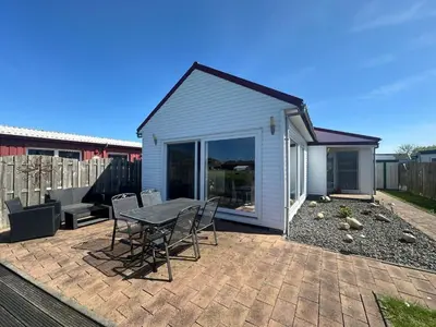 a patio with a table and chairs and a house at Holiday Home Auszeit direkt am Wasser by Interhome in Wervershoof
