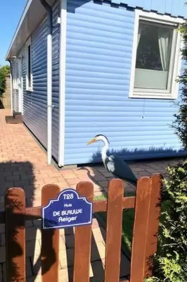 a bird sitting on a fence in front of a house at Holiday Home Haus DE BLAUWE REIGER by Interhome in Wervershoof