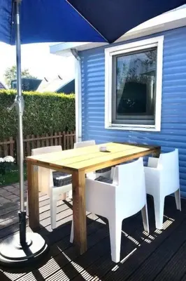 a wooden table with white chairs and an umbrella at Holiday Home Haus DE BLAUWE REIGER by Interhome in Wervershoof