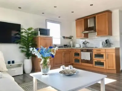 a kitchen with wooden cabinets and a white table at Holiday Home Haus DE BLAUWE REIGER by Interhome in Wervershoof