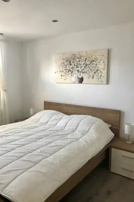 a white bed in a bedroom with a painting on the wall at Holiday Home Haus DE BLAUWE REIGER by Interhome in Wervershoof
