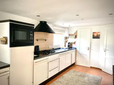 a kitchen with white cabinets and a stove top oven at Holiday Home direkt am See by Interhome in Wervershoof