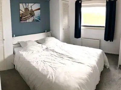 a white bed in a bedroom with a window at Holiday Home direkt am See by Interhome in Wervershoof