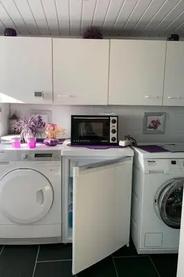 a kitchen with a washing machine and a microwave at Holiday Home direkt am See by Interhome in Wervershoof
