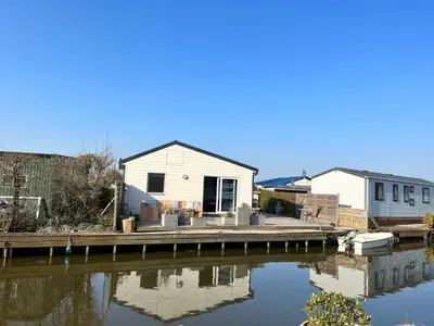a house on a dock next to a body of water at Holiday Home Haus Good Times by Interhome in Wervershoof