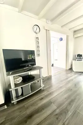 a living room with a television and a clock on a wall at Apartment Familienfreundliches Ferienhaus Angel mit Garten by Interhome in Wervershoof