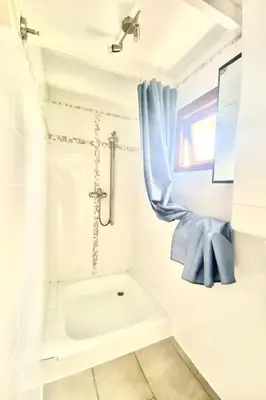 a bathroom with a tub and a shower with a blue curtain at Apartment Familienfreundliches Ferienhaus Angel mit Garten by Interhome in Wervershoof