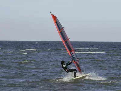 a man on a surfboard with a sail on the ocean at Apartment Familienfreundliches Ferienhaus Angel mit Garten by Interhome in Wervershoof