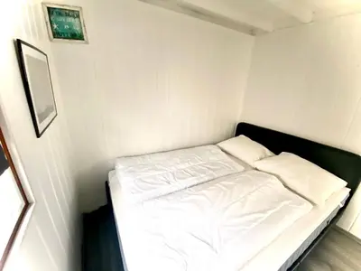 a small white room with a bed in it at Apartment Familienfreundliches Ferienhaus Angel mit Garten by Interhome in Wervershoof