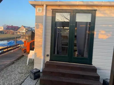 a green door on a house with a deck at Apartment Chalet Welcome direkt am Wasser mit eigenem Steig by Interhome in Wervershoof