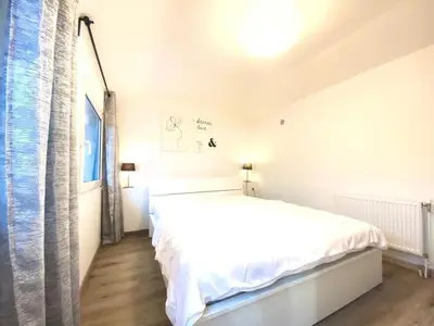 a white bedroom with a bed and a window at Holiday Home Luna by Interhome in Wervershoof