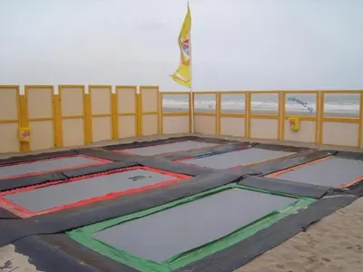 a trampoline park on the beach next to a fence at Holiday Home Strandhaus direkt am Meer by Interhome in Wijk aan Zee