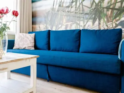 a blue couch in a living room with a table at Holiday Home Strandhaus direkt am Meer by Interhome in Wijk aan Zee