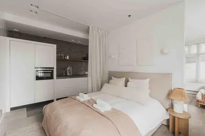 a white bedroom with a large bed and a kitchen at Cozy Traditional Dutch City Apartment close to Amsterdam & Tulips in Purmerend