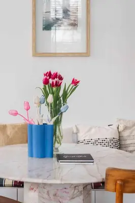a table with a blue vase with flowers on it at Cozy Traditional Dutch City Apartment close to Amsterdam & Tulips in Purmerend