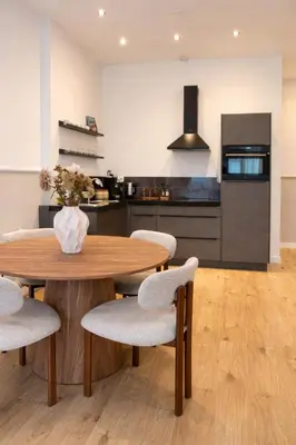 a kitchen with a wooden table and chairs and a kitchen with a refrigerator at Alkmaar Signature Stay -Boutique Apartment in Alkmaar