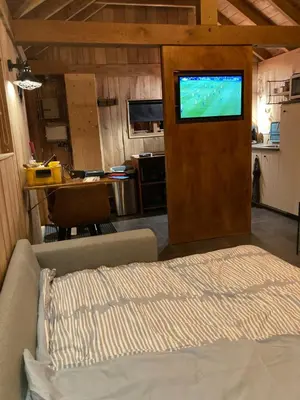 a living room with a bed and a tv on a wall at B&B Tuinhuis Vianen in Vianen