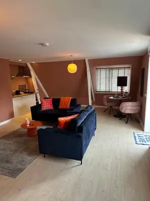 a living room with a blue couch and a table at Little Village - Noordwijkerhout in Noordwijkerhout