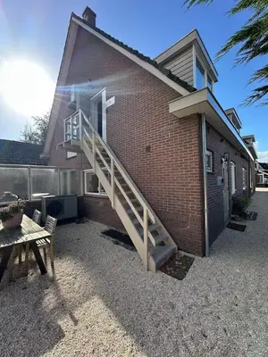 a brick building with a staircase leading up to a house at Little Village - Noordwijkerhout in Noordwijkerhout
