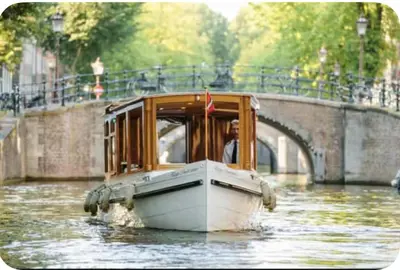 a boat traveling down a river with a man in it at Maison Lumière - Private Rooftop terrace in Amsterdam