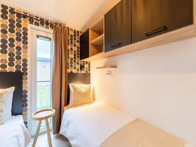 a small bedroom with two beds and a window at Bij de Bakker in Oud-Ade