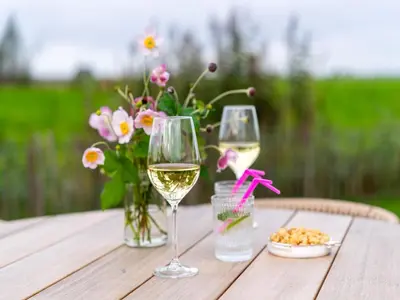 two glasses of white wine on a wooden table with flowers at Bij de Bakker in Oud-Ade