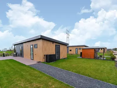 a house with a black roof and a green yard at Bij de Bakker in Oud-Ade