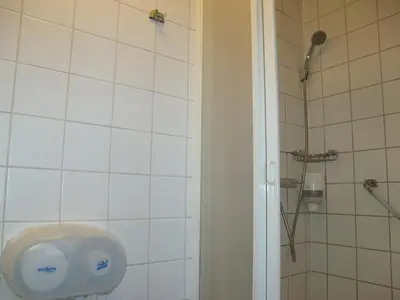 a bathroom with a shower and a soap dispenser on the wall at Zorn Hotel Duinlust in Noordwijk aan Zee