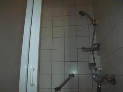 a shower with a shower head in a bathroom at Zorn Hotel Duinlust in Noordwijk aan Zee
