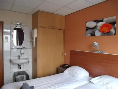 a bedroom with a bed and a sink and a bed sidx sidx sidx at Zorn Hotel Duinlust in Noordwijk aan Zee